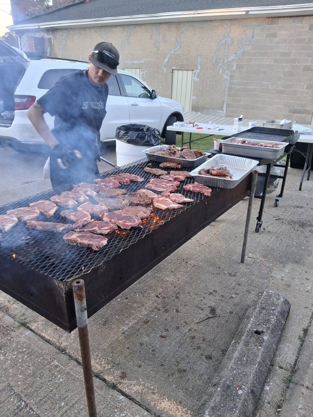 Dr. Getwell's cook flipping steaks on a giant outdoor grill