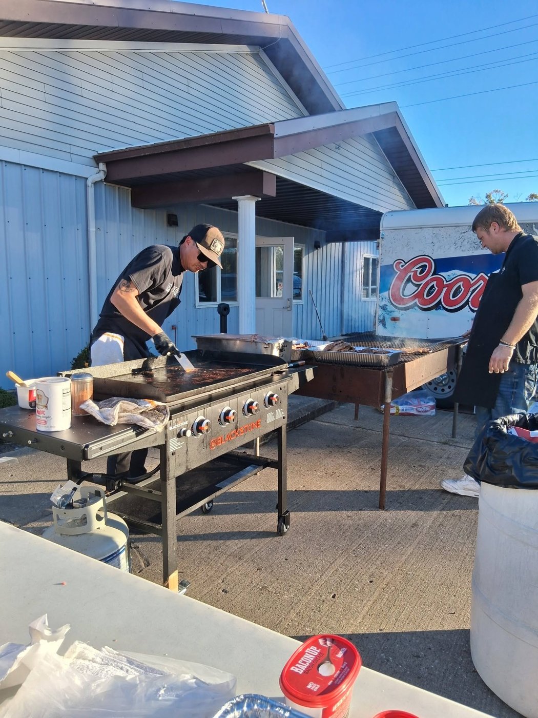 Dr. Getwell's crew cooking on a flat-top griddle and charcoal grill outside the venue